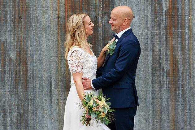 Brudpar framför ruffig vägg - bröllopsfotograf Phia Bergdahl Västervik
