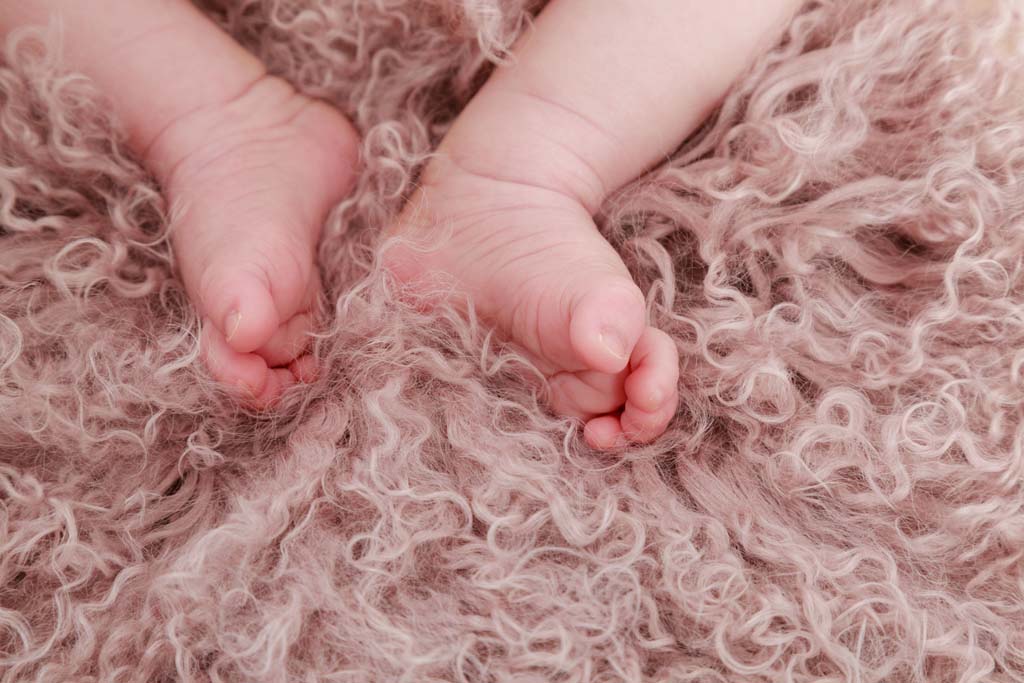 Bebisfötter på rosa fårskinn