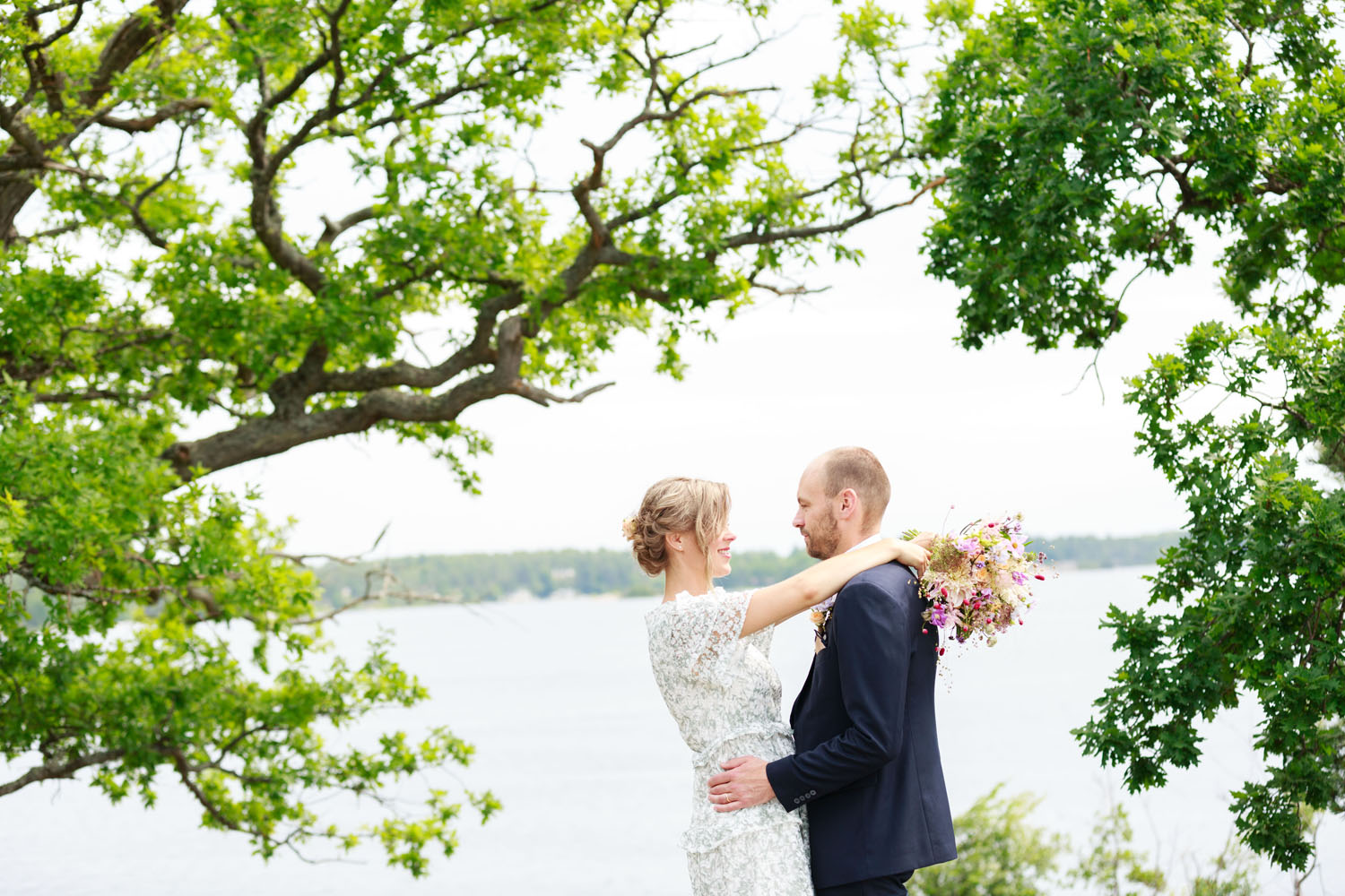 Brudpar som håller om varandra på klippa vid Gränsö slott.